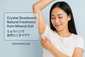 “Beautiful East Asian woman with long dark hair, wearing a white T-shirt, gently applying a crystal deodorant to her underarm with a soft smile. Light blue background, bilingual title text ‘Crystal Deodorant: Natural Freshness from Mineral Salt / ミョウバンで自然にニオイケア’, monomemo.jp at the bottom.”