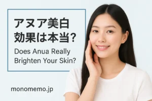 "A beautiful East Asian woman with long black hair gently touching her face, smiling softly against a light blue background, featuring a bilingual text box that says 'アヌア美白効果は本当？ Does Anua Really Brighten Your Skin?' for a MonoMemo.jp skincare article."